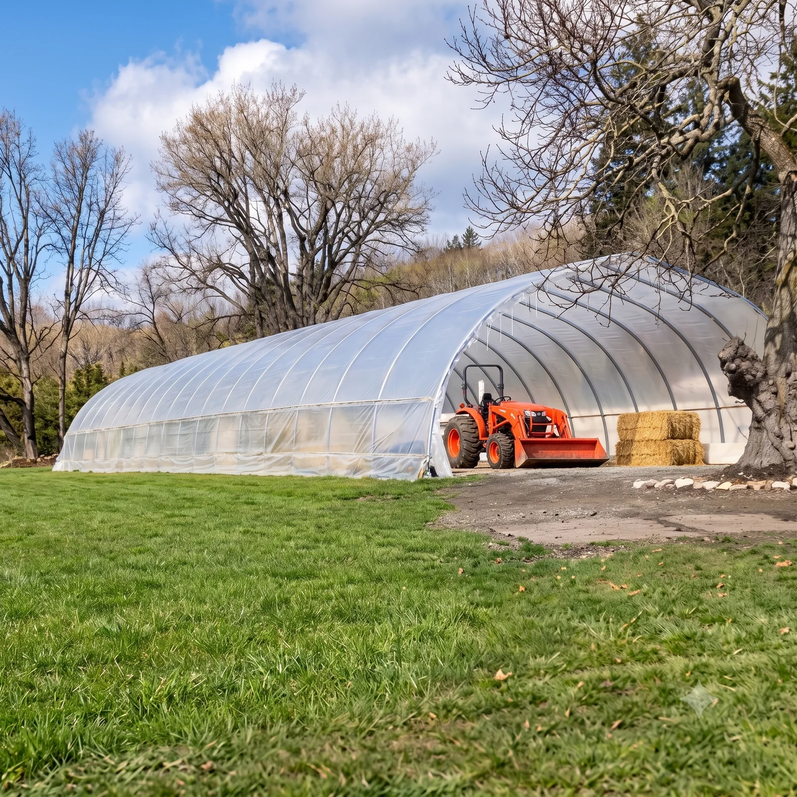 Sun & Steel hoop house in South Surrey, BC with a tractor and stacked hay bales at the open end