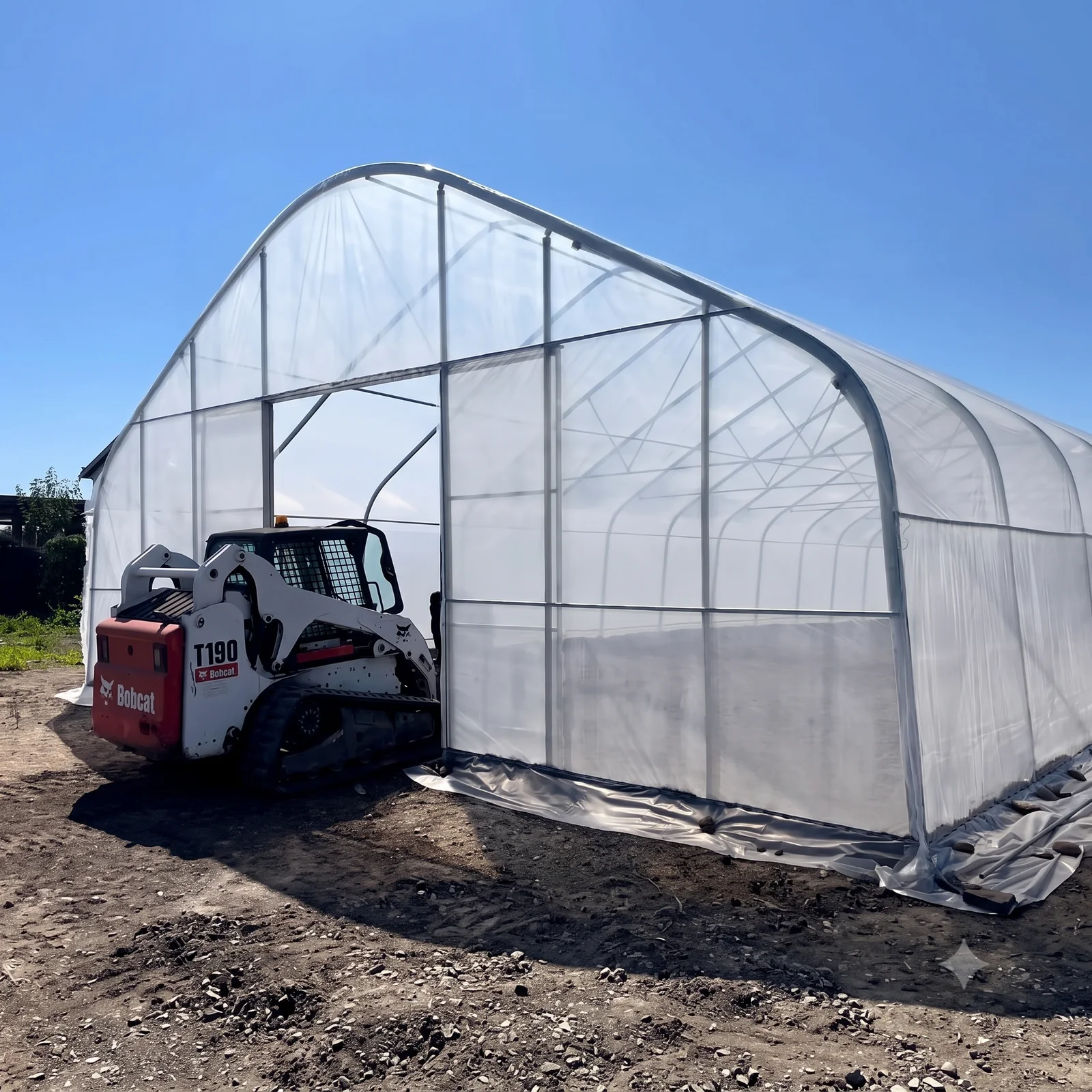 Sun & Steel high tunnel in Surrey, BC with a Bobcat T190 skid steer parked at the open end